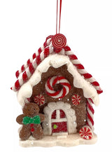Ornaments shaped like gingerbread houses decorated with sugar, frosting, peppermint candies, gummy candies and candy canes. This one has a gingerbread man and a peppermint candy accent.