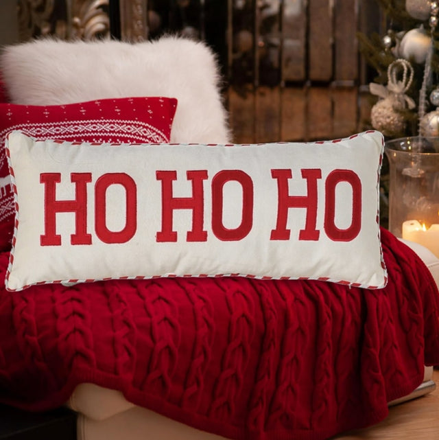 White pillow that reads "HO HO HO" in red, block text. The border is red and white striped.