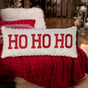 White pillow that reads "HO HO HO" in red, block text. The border is red and white striped.