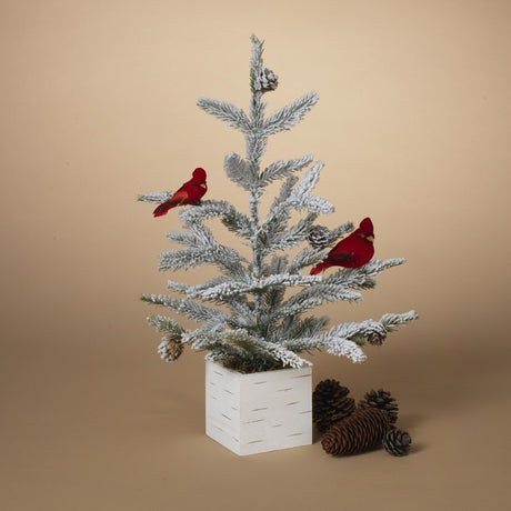 Tabletop tree in a birch planter box. The branches of the tree are dusted with white to mimic snow. The tree is accented with two red cardinal birds and some snow-covered pine cones.