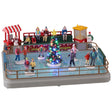 Polyresin, animated figure for a Lemax display. Designed to look like a small ice rink. There are a bunch of people skating around and there's a decorated Christmas tree in the middle of the rink. There's a food vendor, a green bench with people sitting and a popcorn vendor all behind the rink.