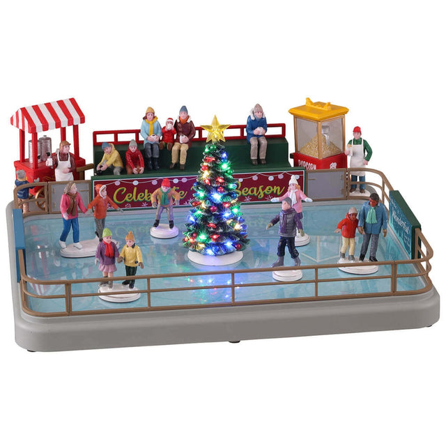 Polyresin, animated figure for a Lemax display. Designed to look like a small ice rink. There are a bunch of people skating around and there's a decorated Christmas tree in the middle of the rink. There's a food vendor, a green bench with people sitting and a popcorn vendor all behind the rink.