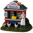 Resin table accent for a Lemax display. Designed to look like a red booth on a grassy patch. There's a sign on the roof that reads "Farm Fresh Eggs. $3.00 a Dozen." There's a cat lounging on the roof and three chickens standing on the ground. The booth is filled with shelves of eggs with a yellow box on the counter. Another sign reads "Honor System. Please put cash in box, thank you." A young girl stands near the booth holding a chicken and a basket of eggs. She's wearing a floppy hat and a white apron.