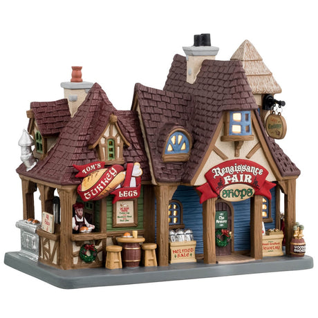 Porcelain lighted building for a Lemax display. Designed to look like a renaissance cottage with different shops. Get a turkey leg at Tom's. Buy a helmet that's on sale at the armory. Get hand-crafted jewelry and wooden swords. Tom's Turkey Legs is a light green color. The other shops are a light blue color.