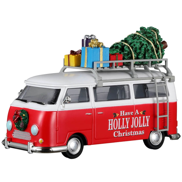 Plastic table accent for a Lemax display. Designed to look like a red and white Volkswagen bus. The sides read "Have a Holly Jolly Christmas" and features little holly leaves and berries. There's a decorated wreath on the front bumper. There's a ladder on the side that leads up to the roof of the van where there's a collection of presents and a Christmas tree.