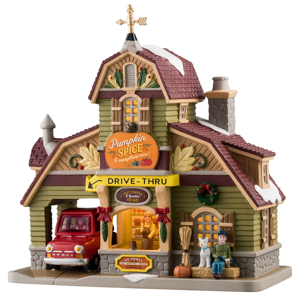 Porcelain lighted building for a Lemax display. Designed to look like a house turned into a drive-thru restaurant. There's a gold wind vine and snow on the roof. There are fall accents as well as wreaths and pine swag decorations. There's a red car ordering food in the drive thru. There's a boy sitting on a bale of hay next to a white dog. You can see a woman inside the building serving coffee.