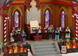 Resin lighted building for a Lemax display. Designed to look like a choir performing at a pavilion. There's a large organ, kids dressed like elves, two dogs, two peppermint candy cane accents, a decorated garland on the roof and a sign that reads "Joy to the World." The ceiling of the pavilion is decorated with different colored poinsettias.