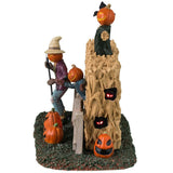 Plastic village accent for a Lemax Spooky Town display. Designed to look like three scarecrows with jack-o-lantern heads coming out of a cornfield. There are glowing red eyes and pumpkins.