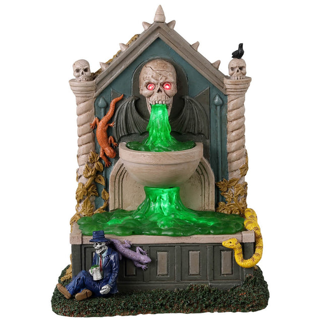 Resin village accent for a Lemax Spooky Town display. Designed to look like a well. The spout where the water is coming from is a skull with red eyes and bat wings. There are snakes and salamanders and a small skeleton man wearing a suit sitting at the bottom. The water is actually a bright green color.