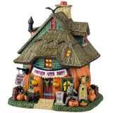 Porcelain lighted building for a Lemax display. Designed to look like a cabin made out of a pumpkin. There's a skeleton sitting in front of the house and a black cat and jack-o-lantern accents. There's a sign above the front door that reads "PUMPKIN PATCH PARTY."