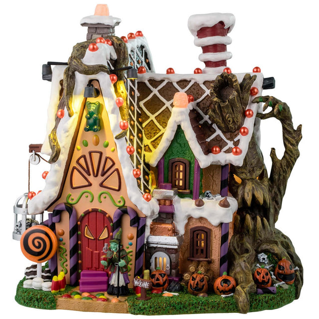 Resin lighted building for a Lemax display. Designed to look like a cabin made out of candy and frosting. There's a spooky tree growing on the side of the cabin and is also growing through the roof. There's a witch standing at the front door.