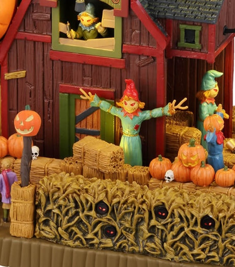 Resin lighted building for a Lemax display. Designed to look like a red barn with a pumpkin patch in front of it. There are scarecrows and jack-o-lanterns. There are weird pumpkin monsters flying above the barn. There are red glowing eyes inside the bales of hay.