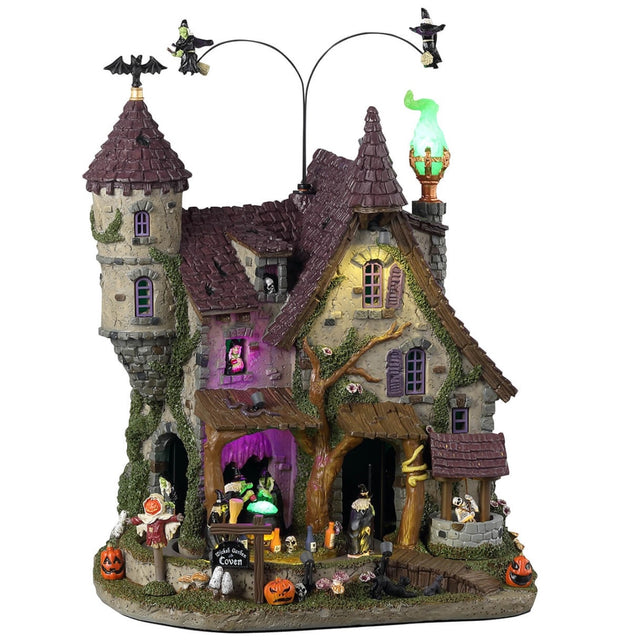 Resin lighted building for a Lemax display. Looks like a cottage with a moss covered tower. There are witches flying above and monsters and witches and a scarecrow and pumpkins.
