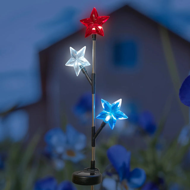 Solar powered garden stake with three stars on it. One star shines red, one star shines pure white and one star shines blue.