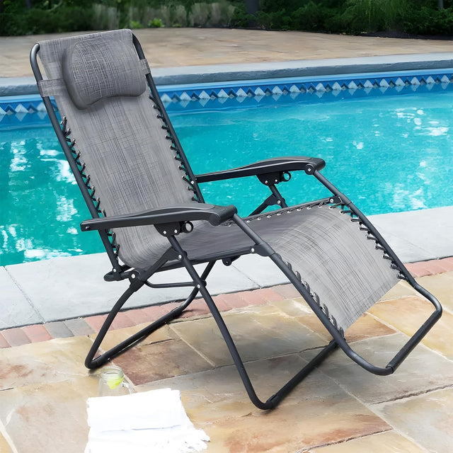 Folding recliner chair with a headrest. There are different color options. This image shows a black frame chair with grey sling fabric. It's sitting on a stone patio next to an inground pool.