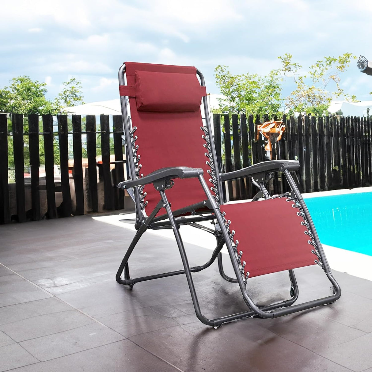 Folding recliner chair with a headrest. There are different color options. This image shows a black frame chair with burgundy sling fabric. It's sitting on a stone patio next to an inground pool.