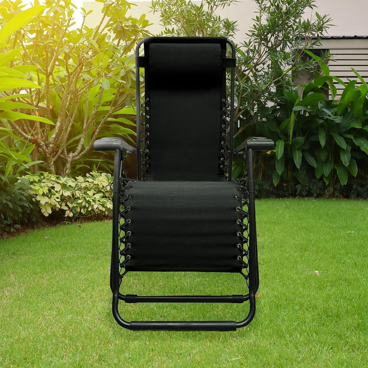 Folding recliner chair with a headrest. There are different color options. This image shows a black frame chair with black sling fabric. It's sitting on grass in a sunny backyard. This is the view from the front.