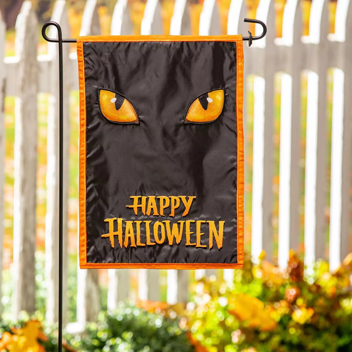 Outdoor Halloween flag. Features an orange border and a shiny, black background. It also features two bright, yellow-orange eyes and a message that reads "HAPPY HALLOWEEN."