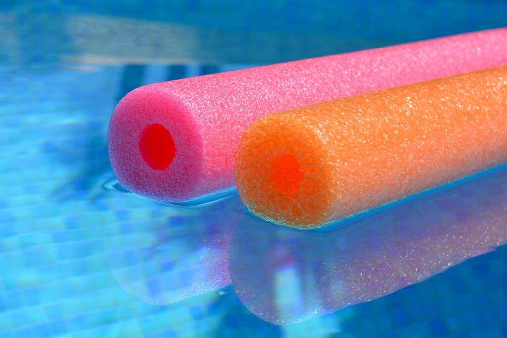 This is an up close view of a pink and an orange noodle floating on the surface of the water.