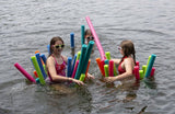 This is a lifestyle image showing three girls riding a bunch of different pool noodles in a lake.