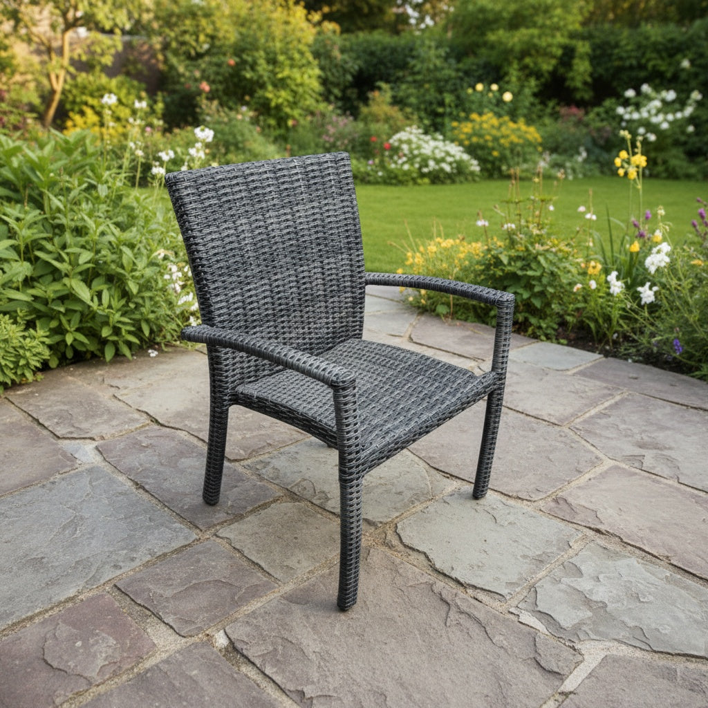 This is a lifestyle image showing this specific armchair on a stone patio in a grassy backyard.