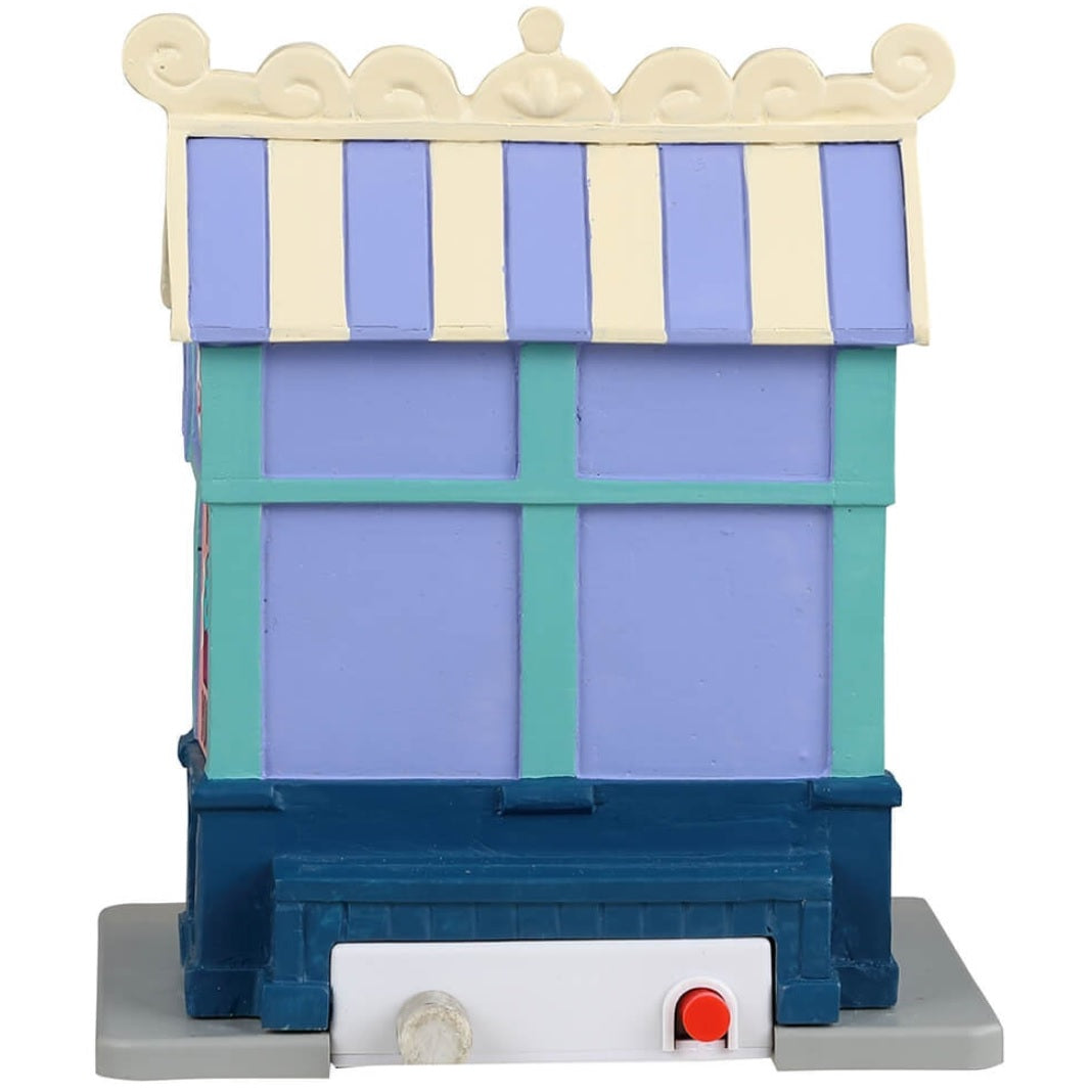 Resin village accent for a Lemax display. Designed to look like a cupcake vendor booth. It's run by Rosette and it's sweets to go. The colors of the booth are light purple, tan, pink, light blue and dark blue.