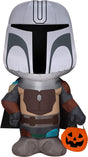 Halloween inflatable shaped like The Mandalorian from the Star Wars universe. He's holding a treat tote bag that looks like a carved pumpkin.