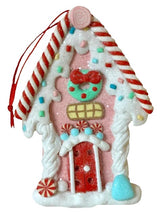 One gingerbread house is teal with a holly leaf accent. One gingerbread house is pink with a wreath accent. One gingerbread house is brown with a peppermint accent. Each ornament features faux candy canes, frosting and gum drop accents.