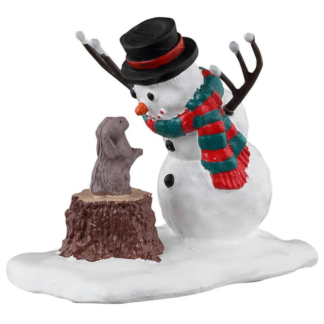 Resin village accessory for a Lemax display. Designed to look like a snowman wearing a top hat and a green and red striped scarf. The snowman is looking down at a bunny standing on a tree stump.