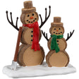 Resin village accessory for a Lemax display. Designed to look like two snowmen made out of wood. There's an axe on the ground next to them. One snowman is wearing a red scarf and the other is wearing a green scarf.