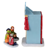 Resin village accent for a Lemax display. Designed to look like a booth decorated to look like a mini theatre with a red curtain. There are two puppets inside and four kids watching.