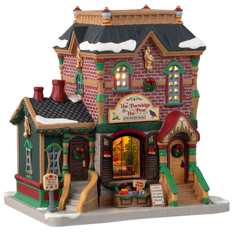 Porcelain lighted building for a Lemax display. Designed to look like a brick building decorated for Christmas with wreaths and garlands. There's snow on the roof and on the sidewalk. 