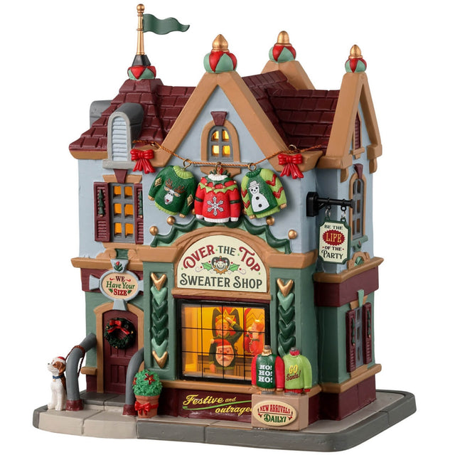 Porcelain lighted building for a Lemax display. Designed to look like a sweater shop. There are a string of sweaters hanging in front and a display of sweaters on the sidewalk. In the window you can see people trying on sweaters. There's a dog wearing a Santa hat waiting at the front door.