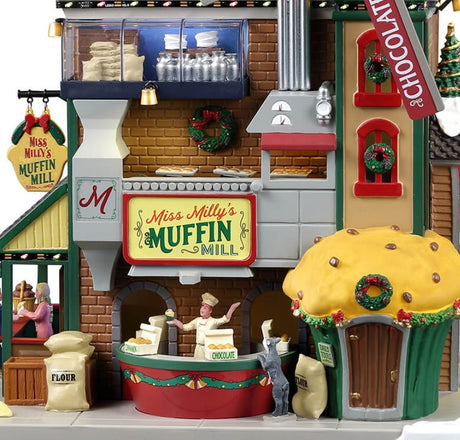 Plastic lighted building for a Lemax display. Designed to look like a large muffin shop. There's a large red windmill with a large muffin statue on the roof. The windmill reads "BANANA, CINNAMON, CHOCOLATE, BLUEBERRY."