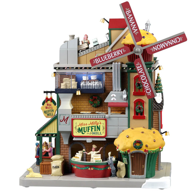 Plastic lighted building for a Lemax display. Designed to look like a large muffin shop. There's a large red windmill with a large muffin statue on the roof. The windmill reads "BANANA, CINNAMON, CHOCOLATE, BLUEBERRY."