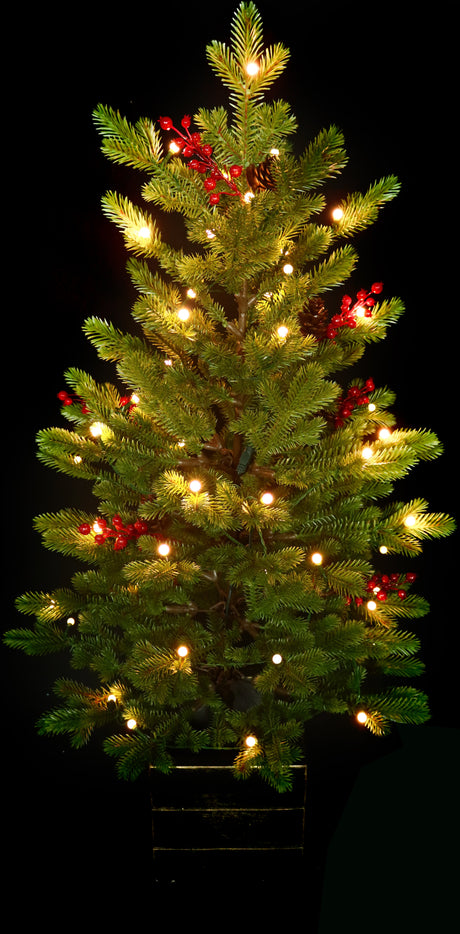 Artificial tree pre-lit with Starry lights. Tree is decorated with red berries and is in a pot.