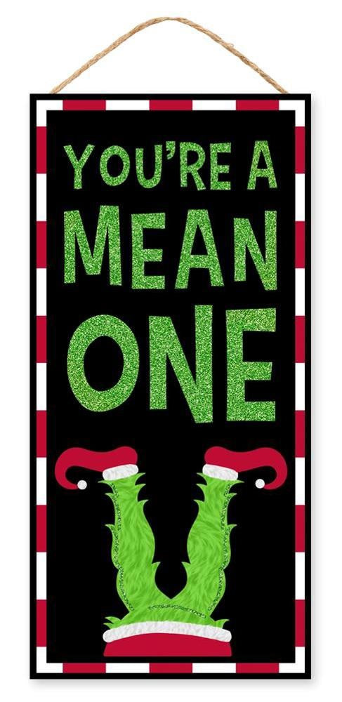 Hanging sign decoration for Christmas. The border is red and white striped. The background is black and reads "YOU'RE A MEAN ONE" and features Grinch legs with red elf shoes. The text is decorated with green glitter.