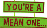 Hanging decoration for Christmas. The top is a red Santa hat with a white cuff and a white ball at the tip of the hat. Underneath that is a sign that reads "YOU'RE A MEAN ONE" and the text is colored with red glitter. Under that are two green furry legs with red elf shoes.