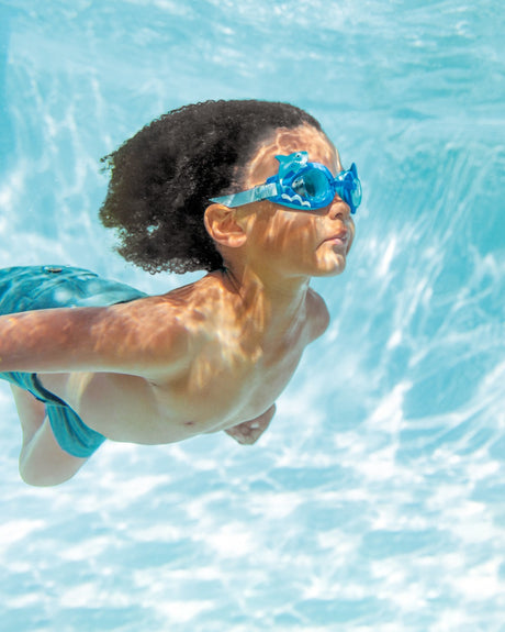 Fun swimming goggles for kids. One features light blue eye cups with pink butterflies and flowers on it with a yellow strap. One features red eye cups that are shaped like crabs with a yellow strap. One features blue eye cups with light blue smiling sharks and a gray strap.