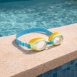 This is a lifestyle image showing a pair of goggles on the side of a pool.