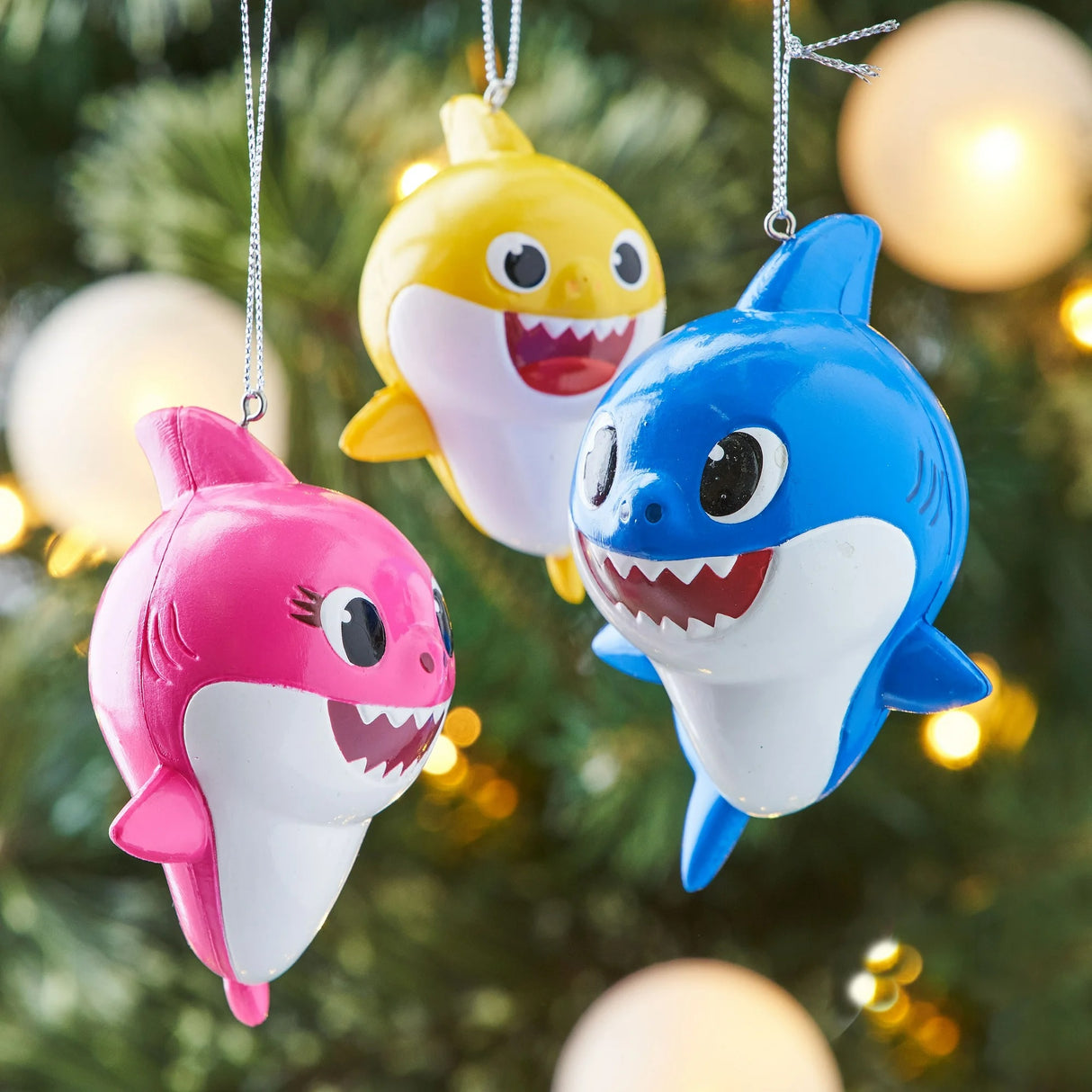 Baby Shark themed ornaments. Baby Shark is yellow. Mommy Shark is pink. Daddy Shark is blue.