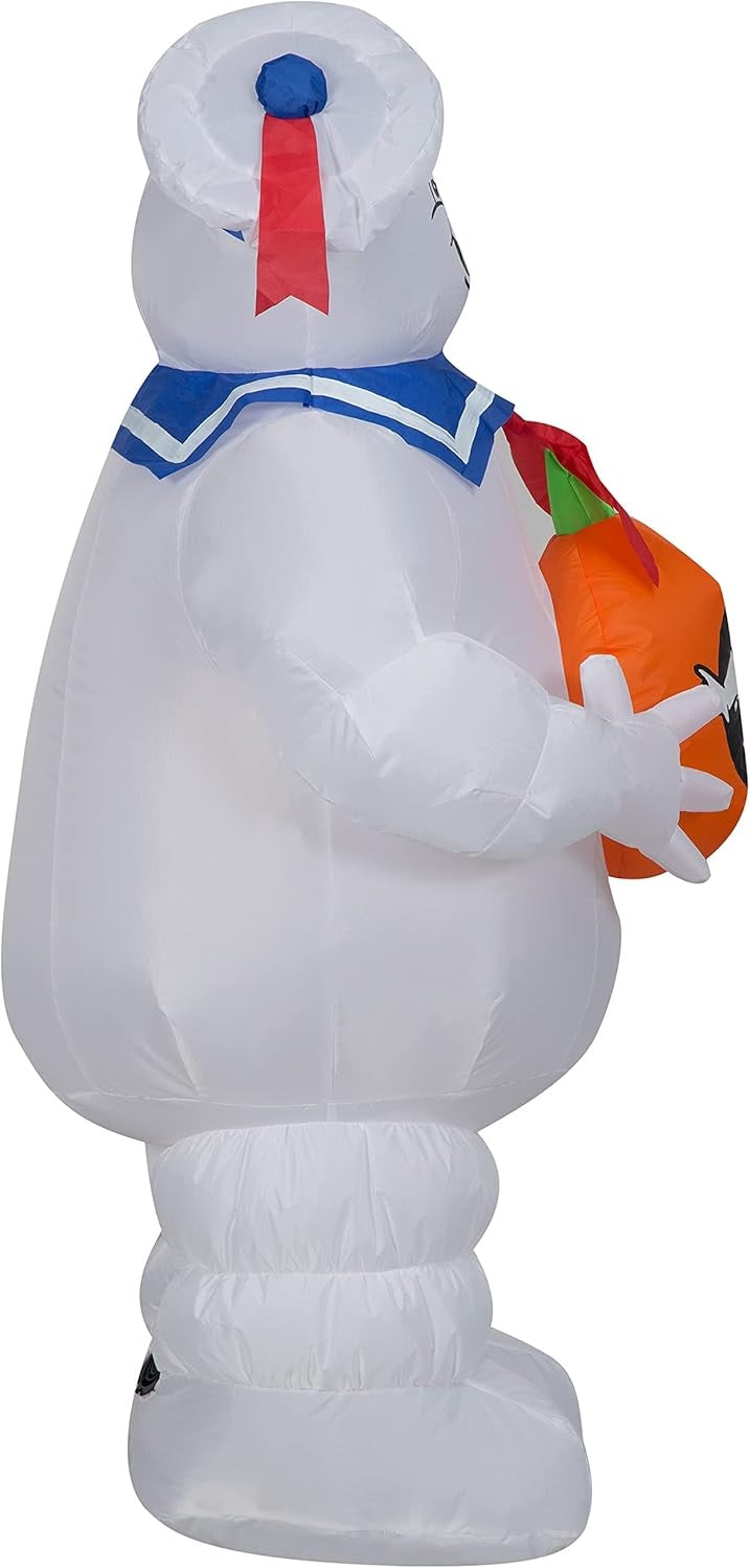 Halloween inflatable shaped like the Stay Puft Marshmallow Man from the movie Ghostbusters. He's holding a pumpkin with the Ghostbusters logo on it.