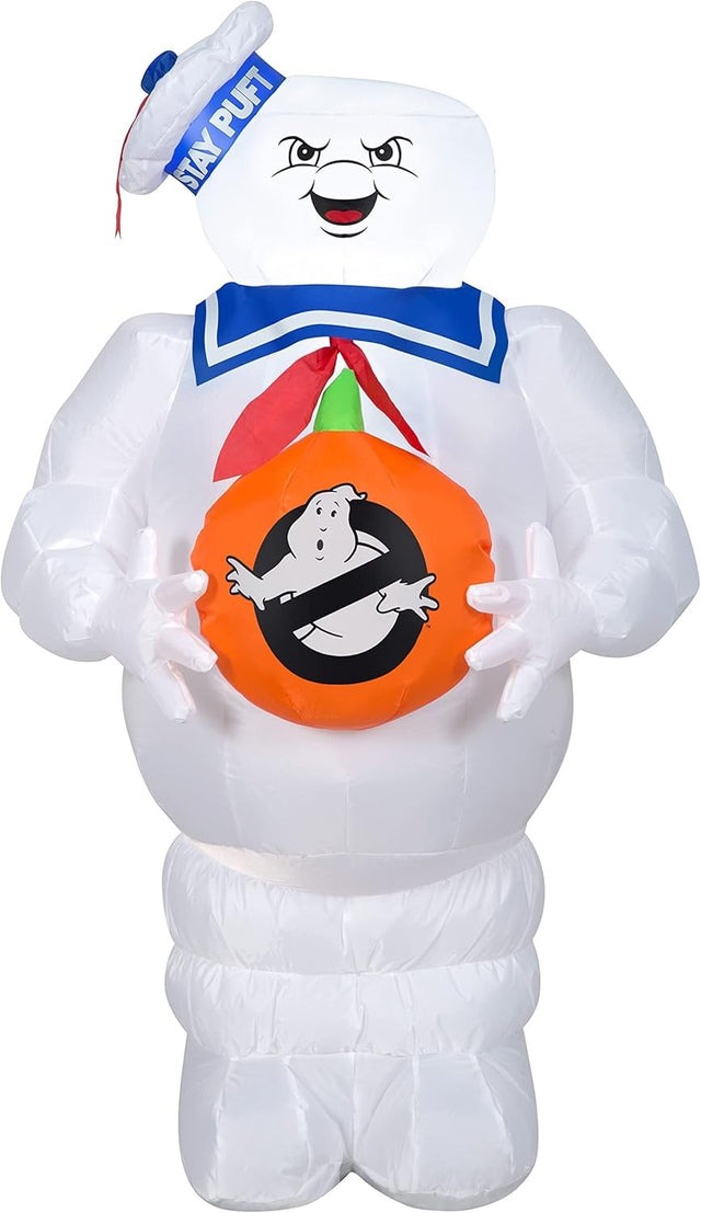 Halloween inflatable shaped like the Stay Puft Marshmallow Man from the movie Ghostbusters. He's holding a pumpkin with the Ghostbusters logo on it.