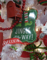 Christmas sign hanging from a jute rope on a Christmas tree with other ornaments and tinsel.