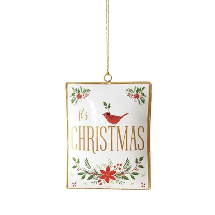 Decorative Christmas ornament. This one is white and features a cardinal, some poinsettias and some holly leaves and reads "It's Christmas" and has a gold border. 