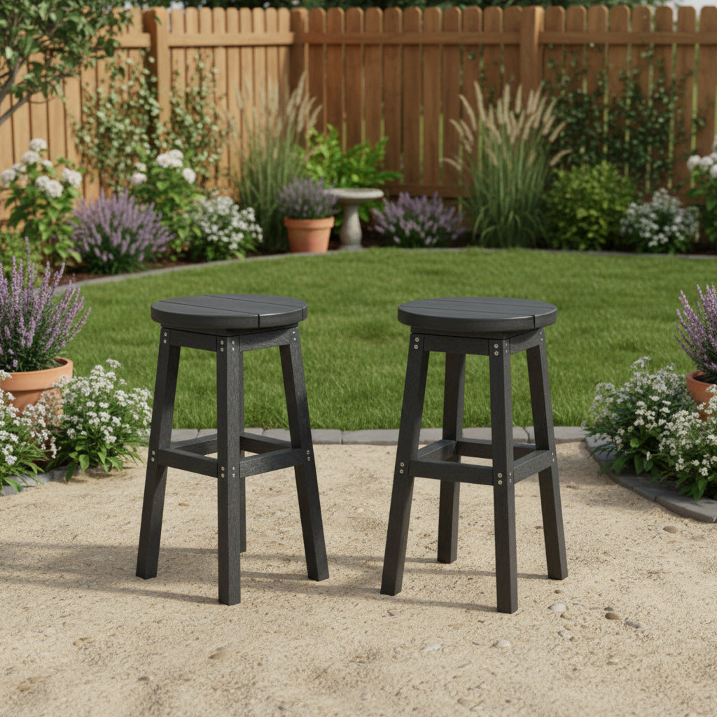 This is a lifestyle image showing two stools on a sandy patio in a grassy backyard surrounded by a wooden fence and lots of potted plants.