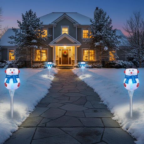 This is a lifestyle image showing four of these snowman pathway lights in the snow in front of a house on a snowy day.