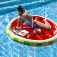 This is a lifestyle image showing a woman resting on this inflatable watermelon float while she reads a magazine.