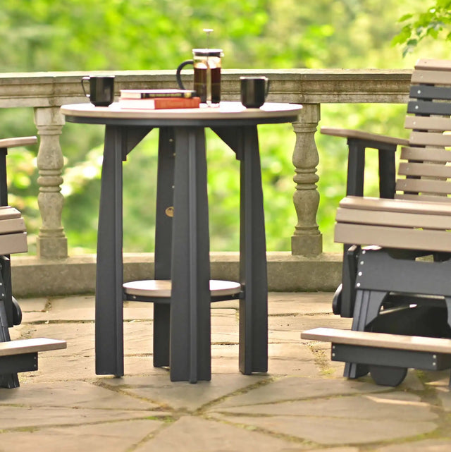 This is a lifestyle image showing a Weatherwood and Black colored Balcony Table between two matching chairs. There are two black mugs on the table.