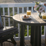 This is a lifestyle image showing the Black colored Balcony Table next to a matching chair on a wooden balcony in a backyard.